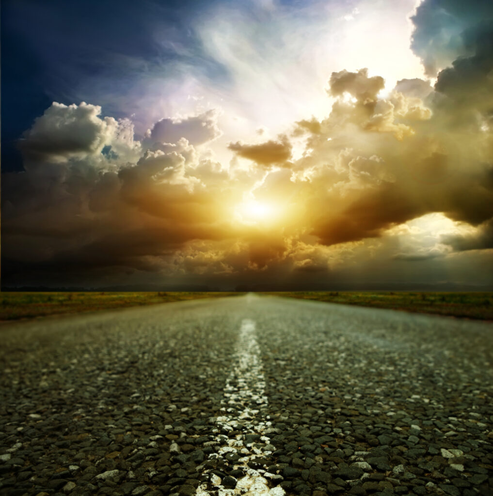 An open road under a storm-lit sky