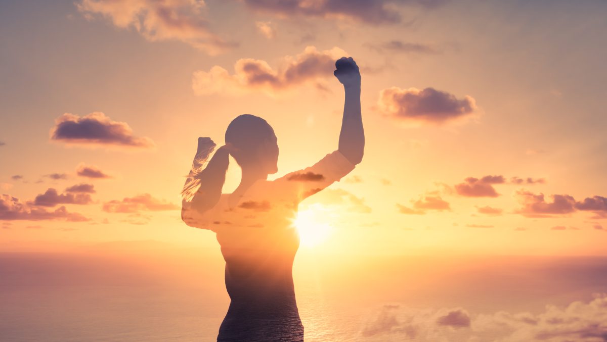 A silhouette with raised arms at sunrise